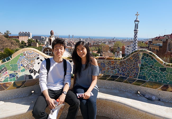 Undergraduate business student Natasha Lim poses with a friend on a colorful mosaic park bench in Barcelona.