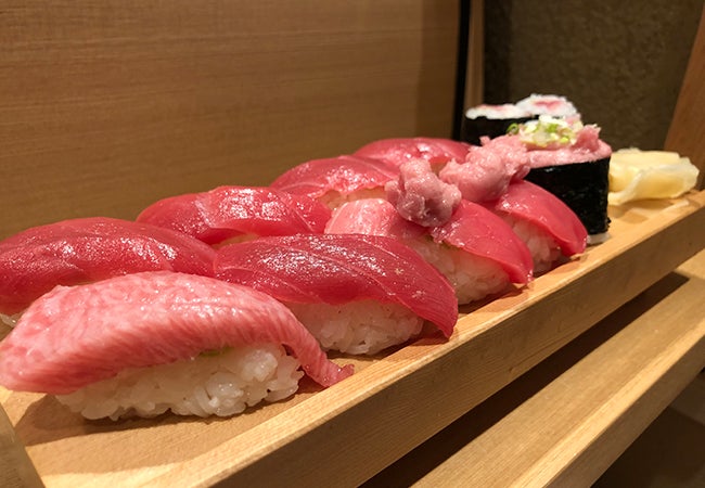 A close-up of two rows of fresh sushi served in a restaurant. 