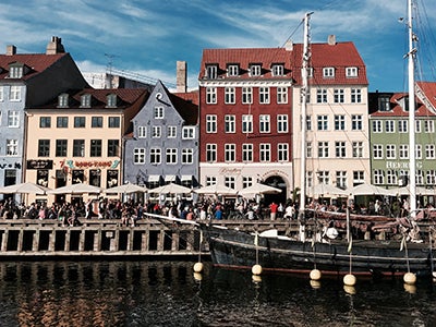 Pedestrians make their way through a row of white tents along a waterway in Copenhagen.