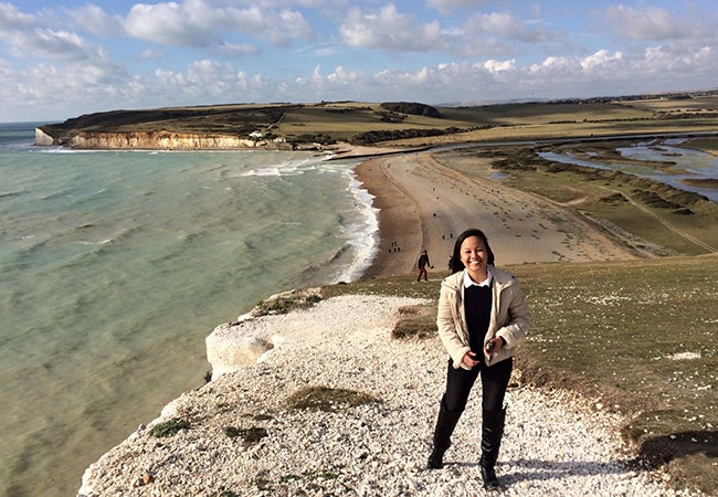 MBA student Kimberly Rodriguez smiles and stands beside a teal sea while studying abroad in London.
