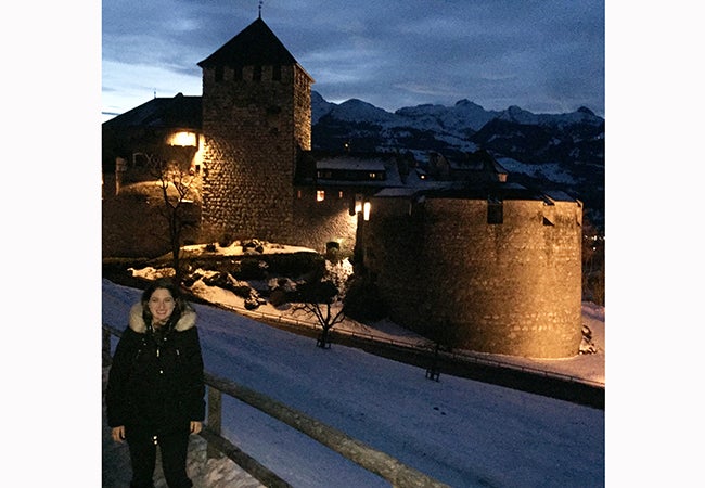 MBA student Ashley Grand stands in front of a small stone building during her travels while studying abroad. 