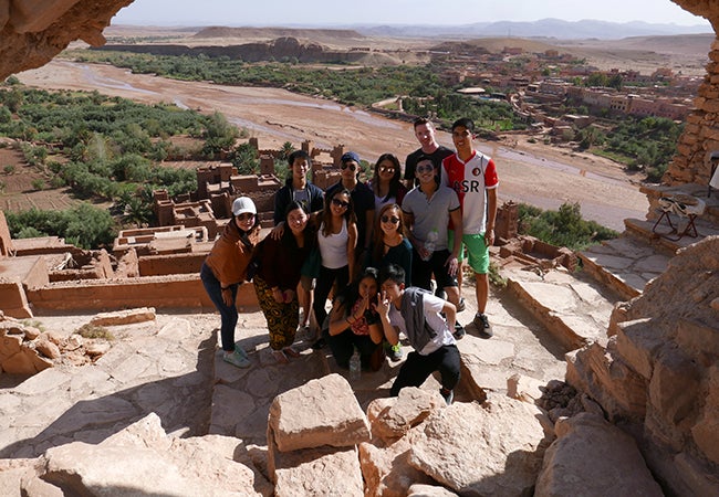 Undergraduate student Matthew Robinson poses near an ancient hillside dwelling with other students while studying abroad in Morocco. 