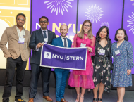 Six alumni pose with an NYU Stern banner at the Reunion 2023 celebration at MoMA.