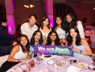 Students posing for photo with We Are Stern banner at a table.