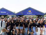 Students wearing NYU Stern shirts stand in front of US Open sign