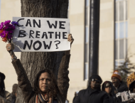 Person holding up a sign that says "Can we breathe now?"