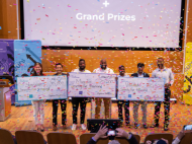Six people holding oversized checks with confetti falling over them