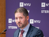 NYU Stern Professor Michael Dickstein speaking at a podium.