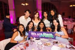 Students posing for photo with We Are Stern banner at a table.