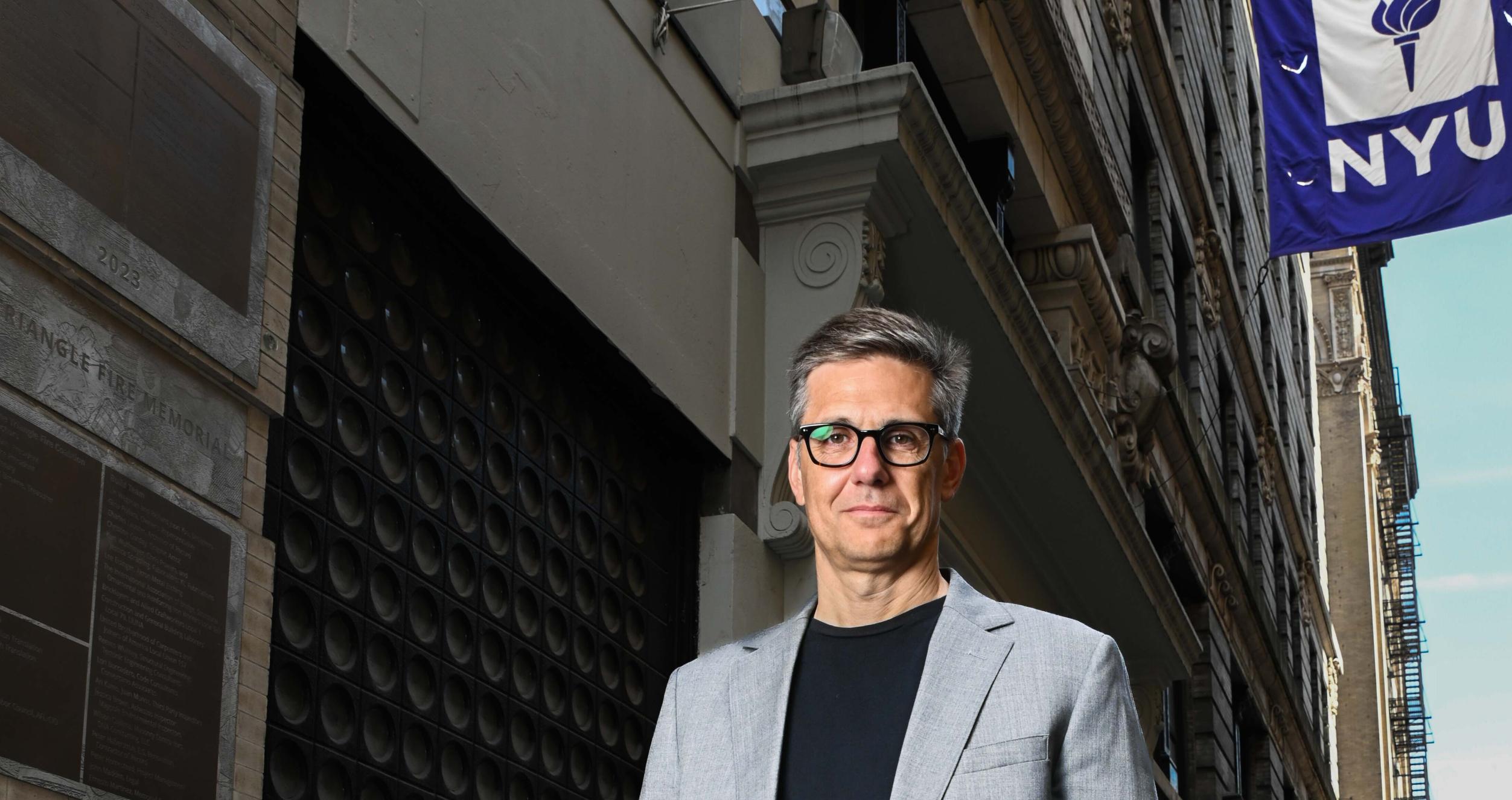 Interim Dean Eggers stands in front of an NYU building. 