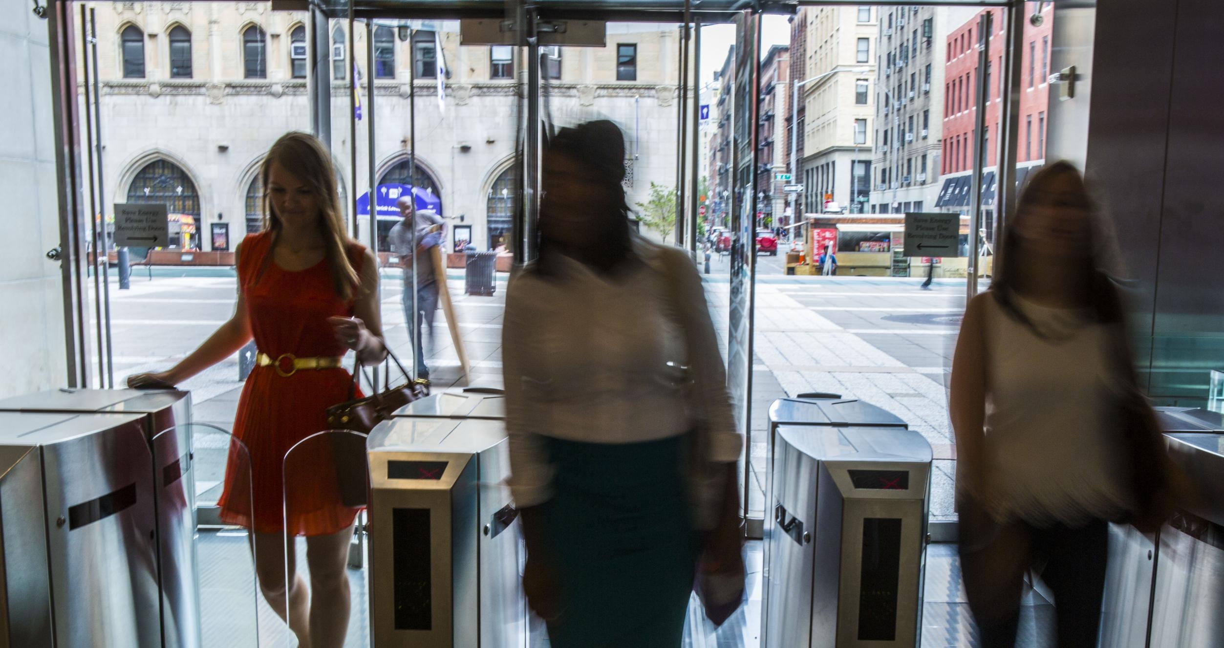 Students entering Tisch Hall Lobby Students walking into a building through glass turnstiles