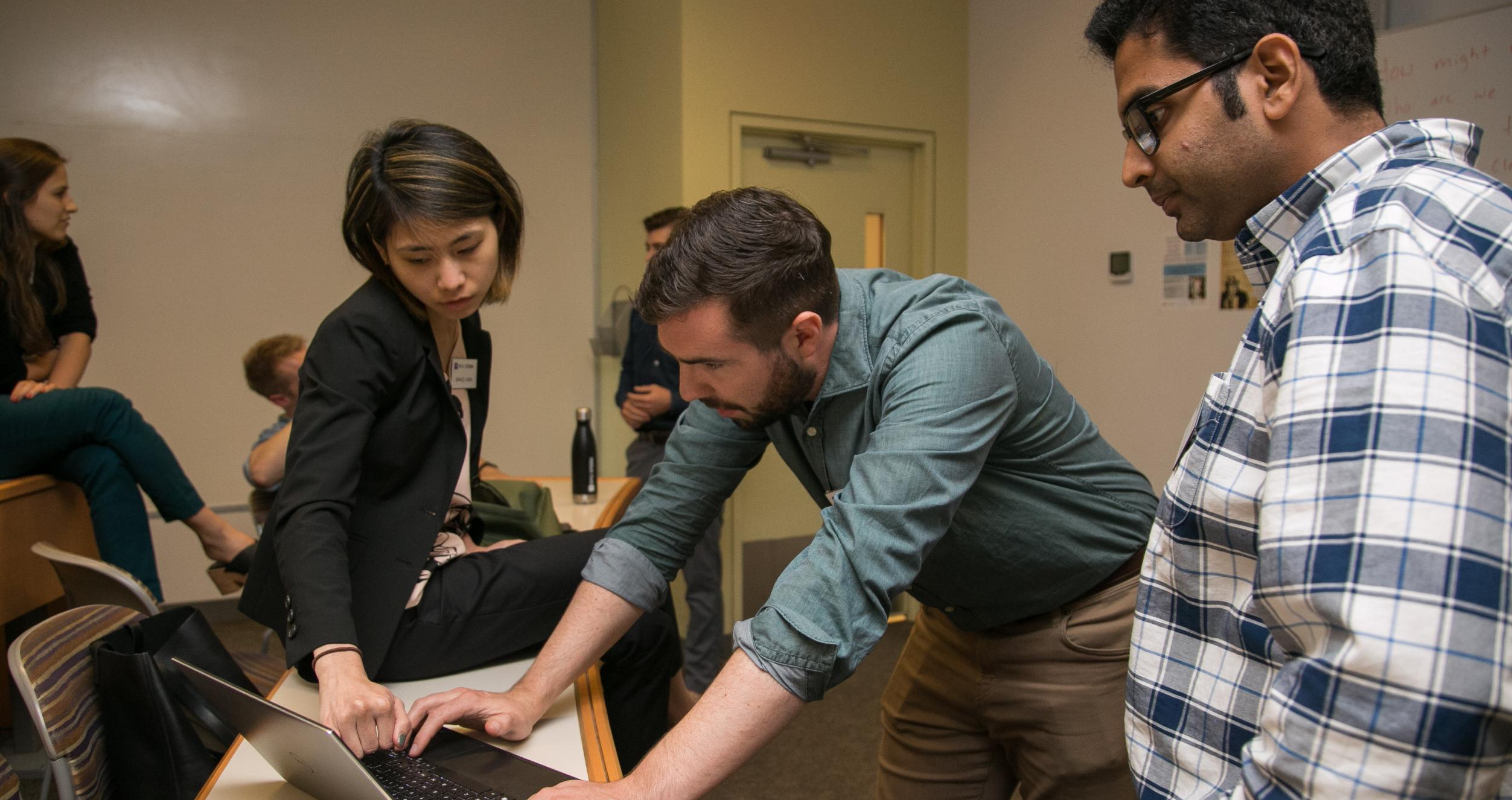 Three MBA students examining a problem on a laptop