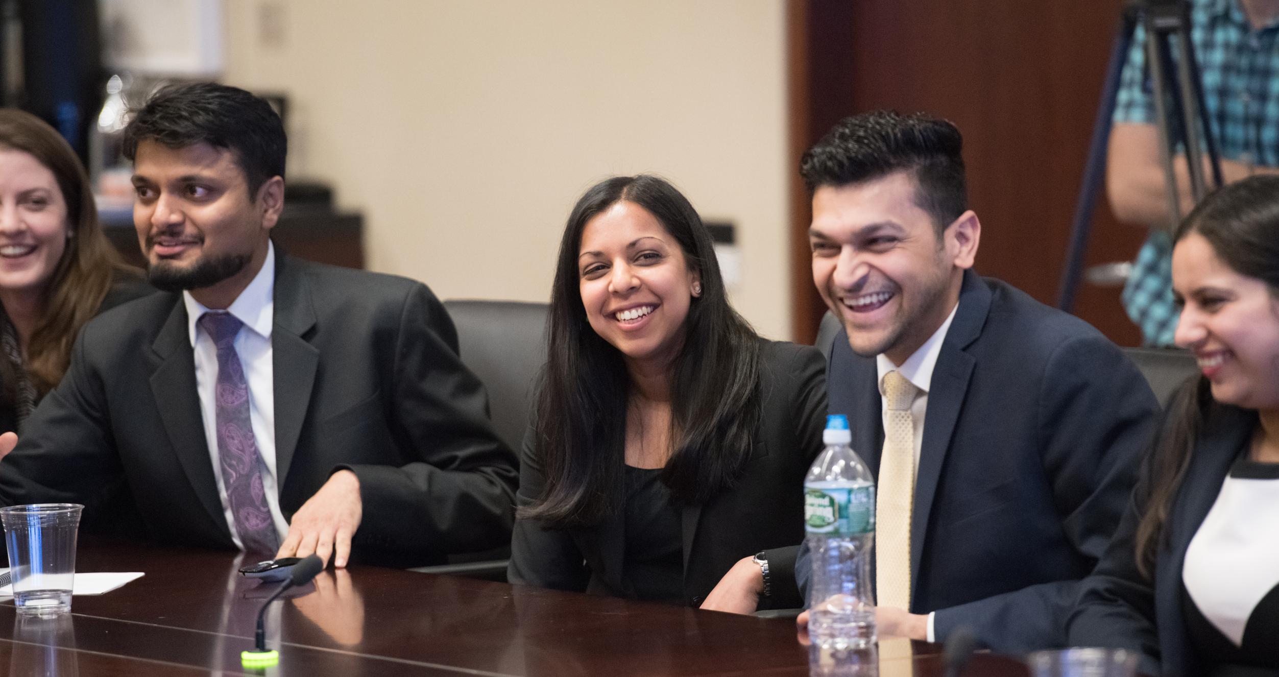 Five students at a conference room table laughing