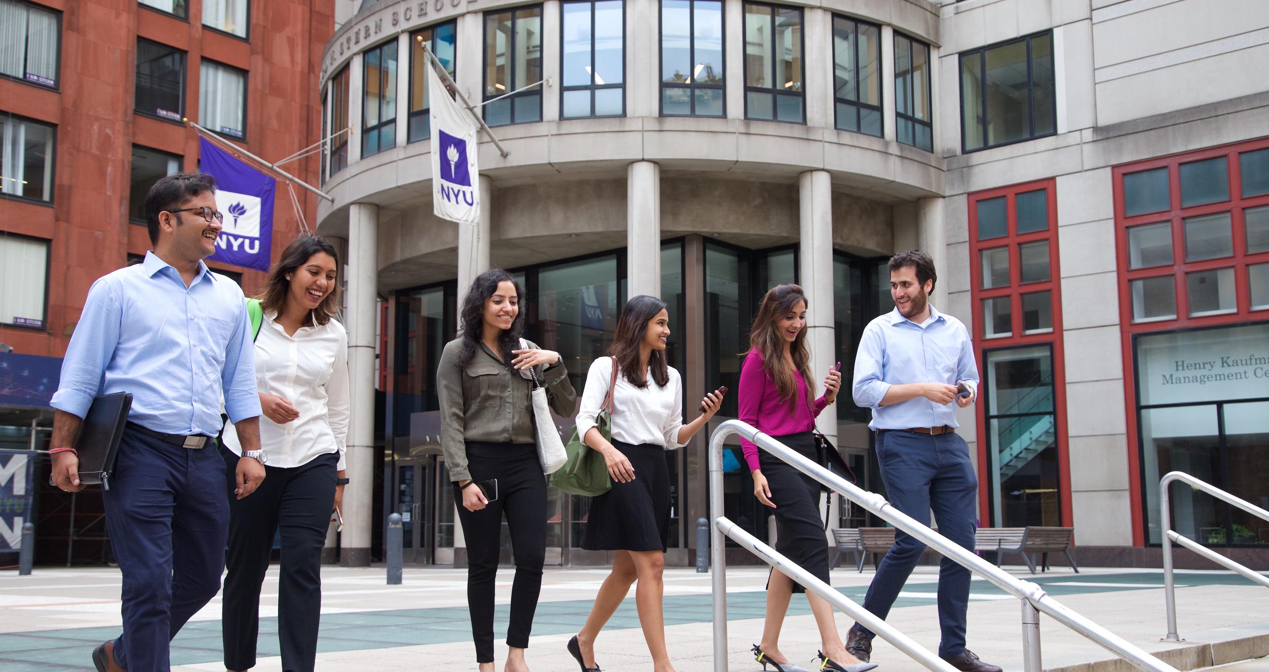 A group of people walking down the steps in front of an NYU building