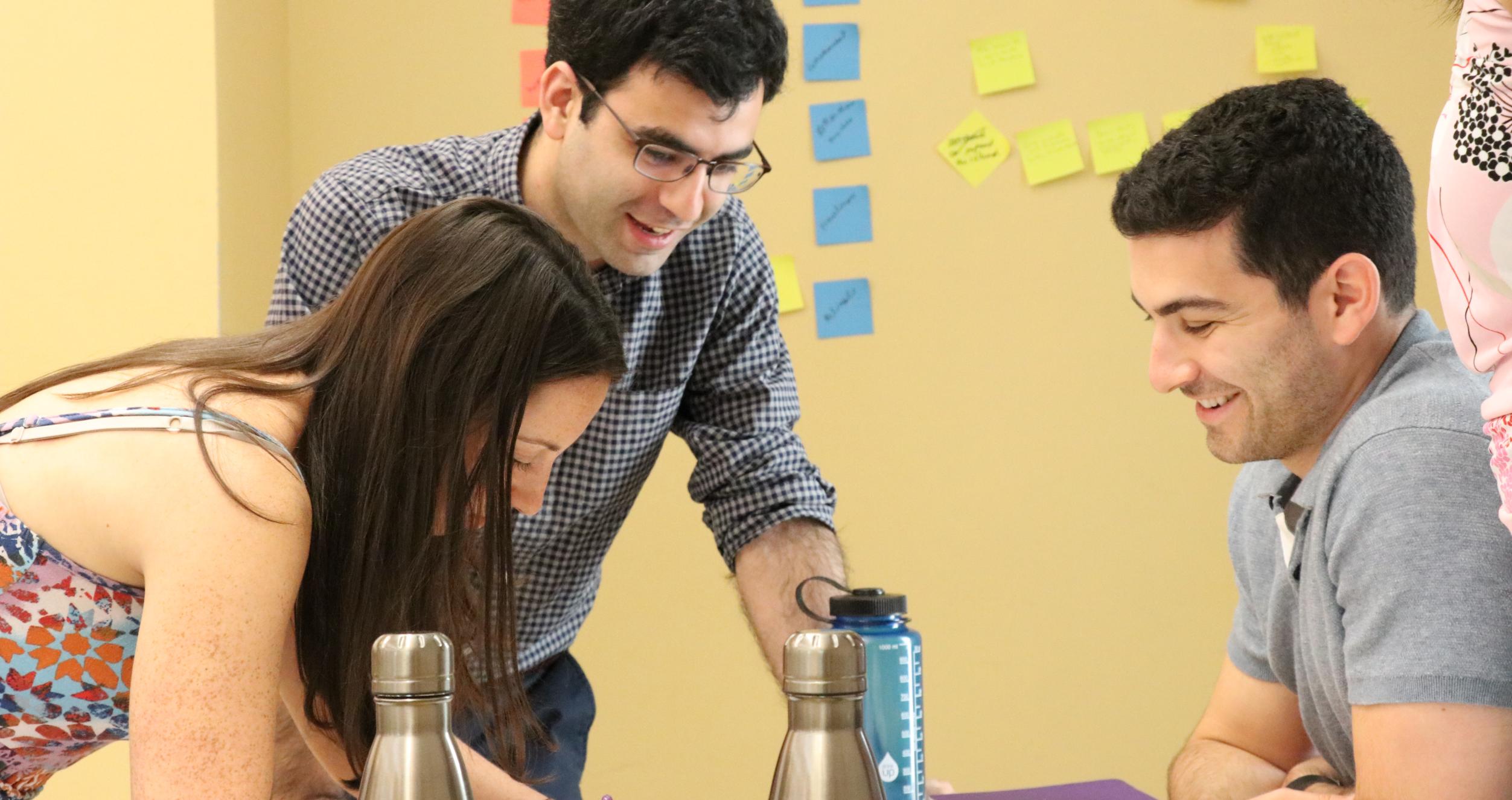 Tech MBA students writing and smiling while solving a problem