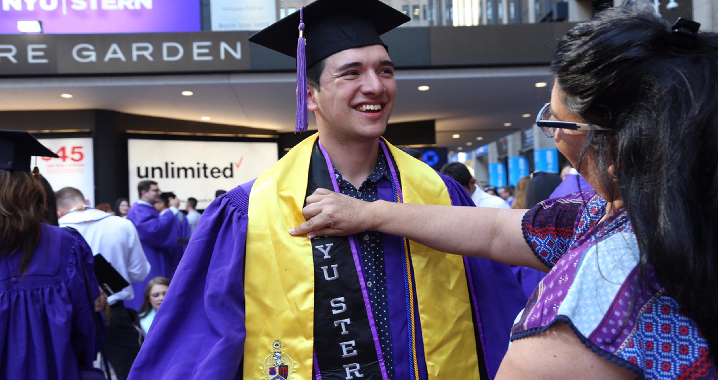 A mom fixes her son's stole at graduation