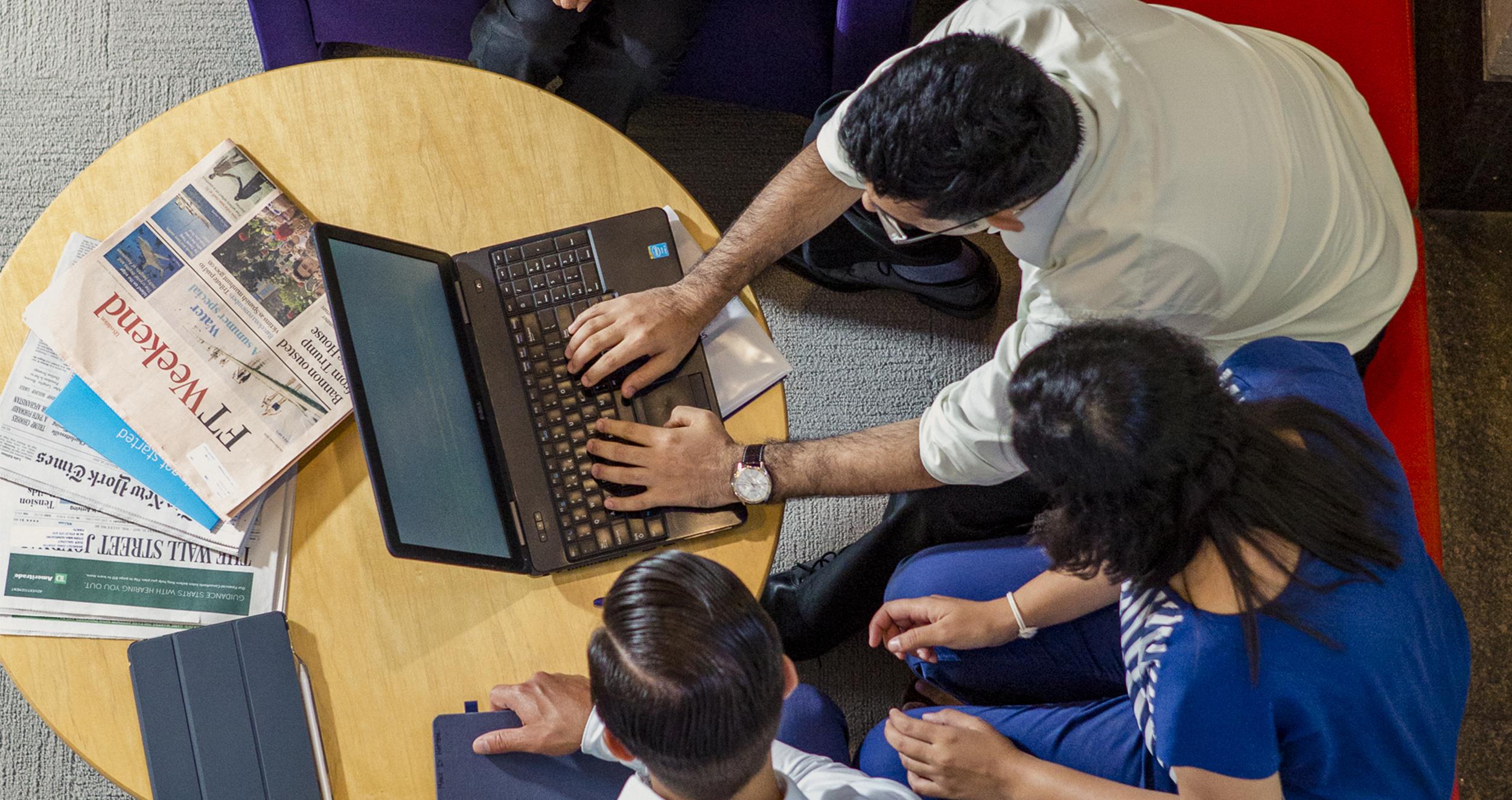 Overhead shot of people working together on a laptop.