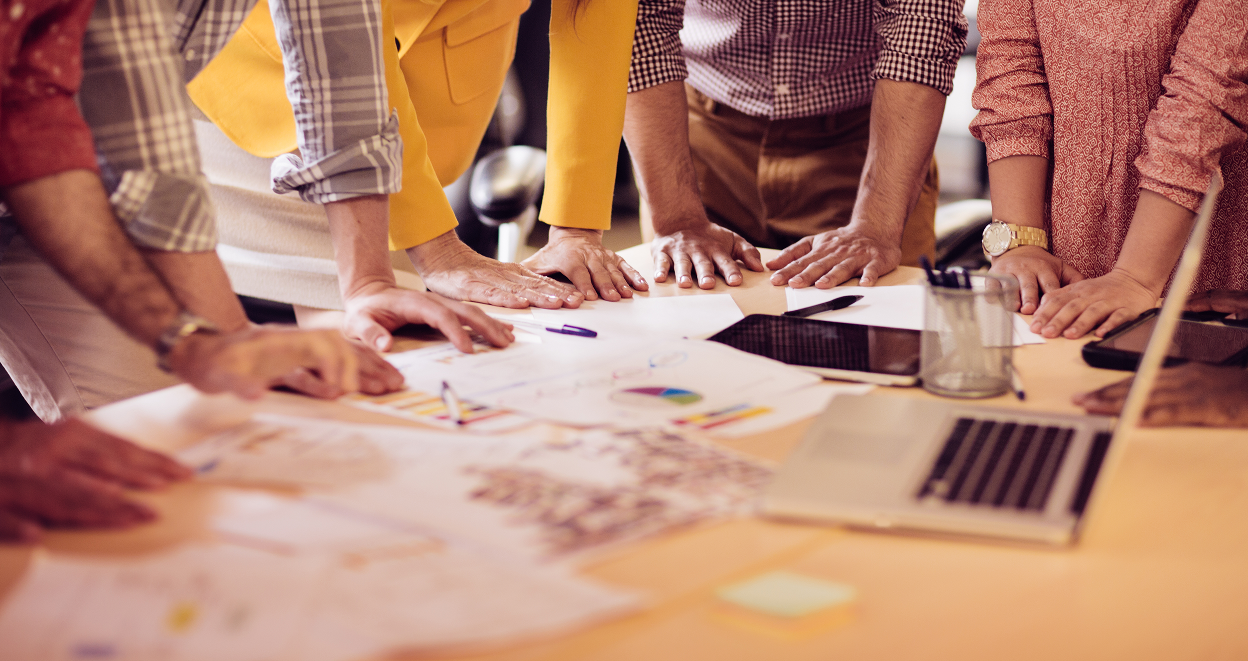 A group of people standing around a table working 