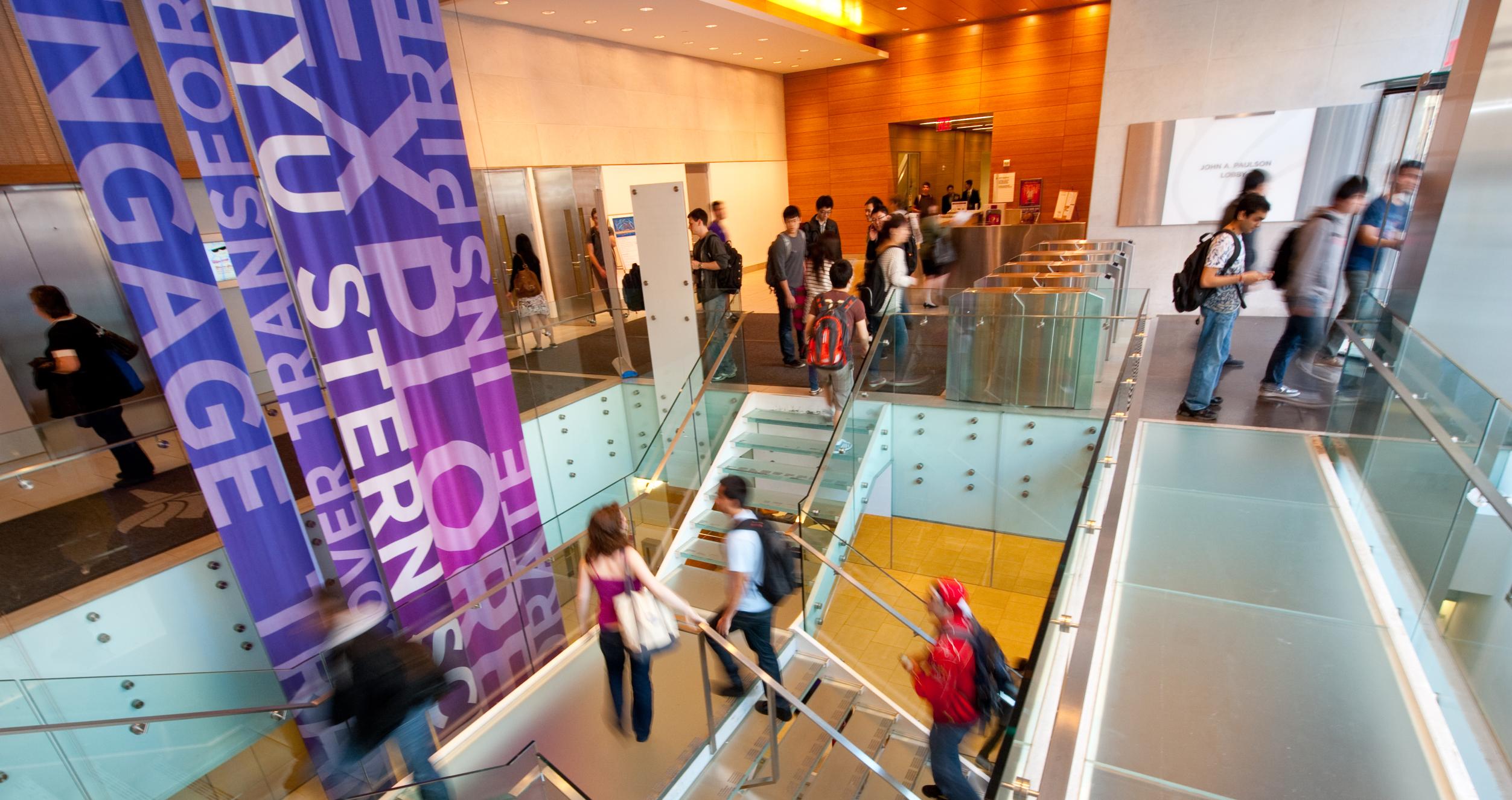 Students walking up the stairs in NYU Stern's Tisch Lobby