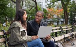 Stern students sit on a bench with a laptop