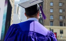 Graduate in cap and gown looking at Empire State Building