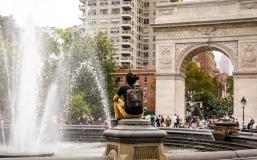 Student sitting near fountain in front of Washington Square Arch