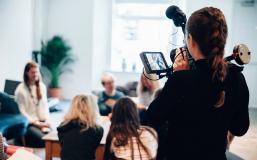 Woman films a group of people talking