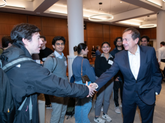 John Paulson (BS ’78) shakes hands with a student