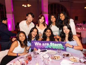 Students posing for photo with We Are Stern banner at a table.