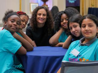 Debra-Ellen Glickstein seated with students at NY Stock Exchange