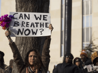 Person holding up a sign that says "Can we breathe now?"