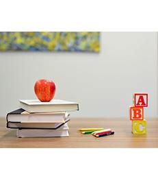 Desk with apple, books, colored pencils and blocks