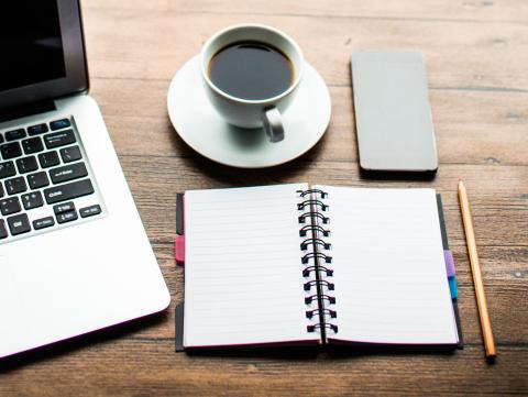 A notebook and cup of coffee on a desk