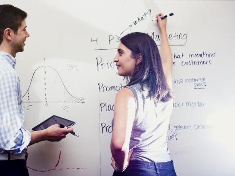 Marketing Alumni Group Students writing about marketing on a white board