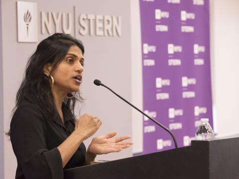 A woman speaking passionately at a podium in front of NYU Stern logo