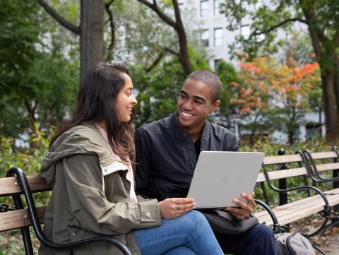 Stern students sit on a bench with a laptop