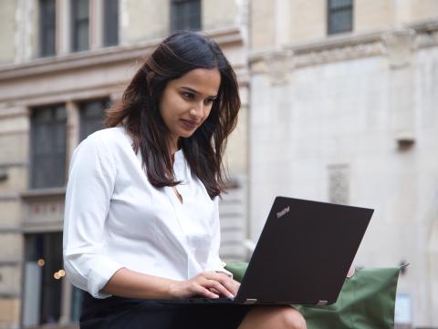 Student sits outside and works on a laptop