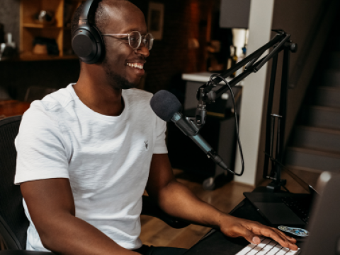 Man sitting at a keyboard in front of a microphone