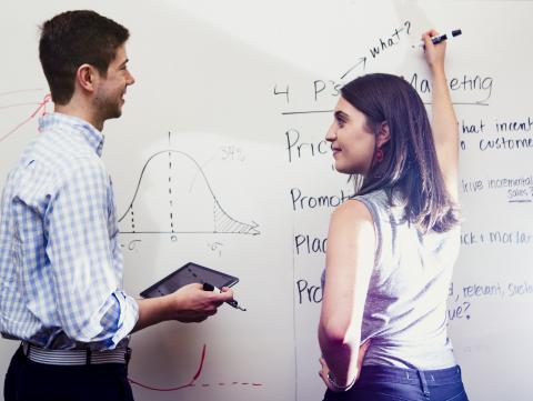 Two people at whiteboard brainstorming