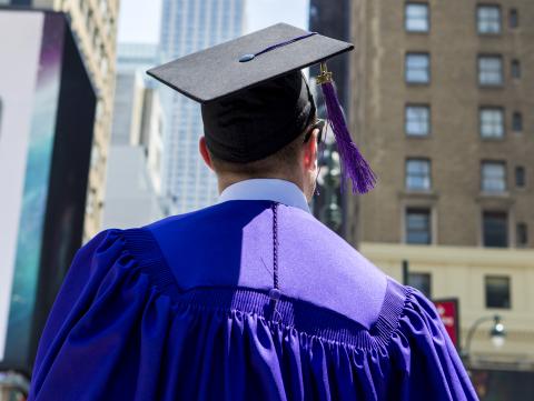 Graduate in cap and gown looking at Empire State Building