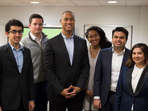 Five students and professor standing in conference room