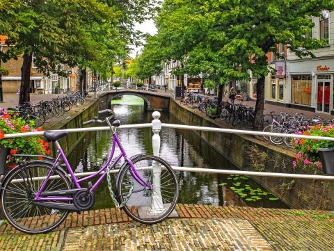 Image of a bridge with a bike on it and many bikes parked along both sides of the canal in The Netherlands