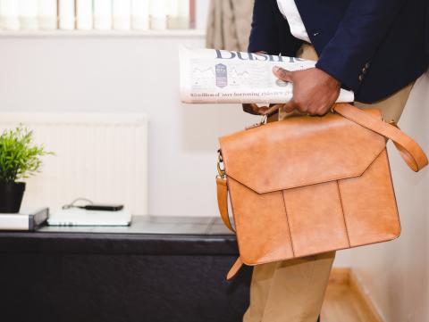 Person holding briefcase and newspaper