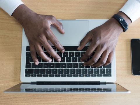 Hands type on a laptop keyboard