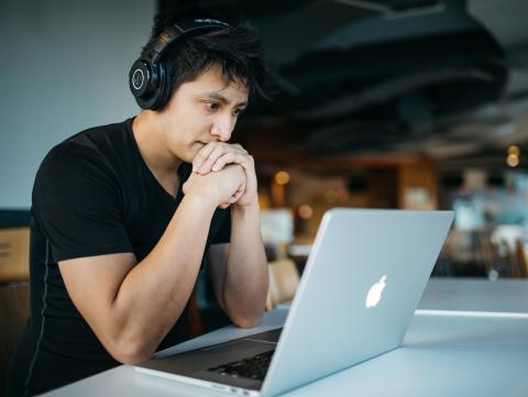 Student wearing headphones looks at a laptop