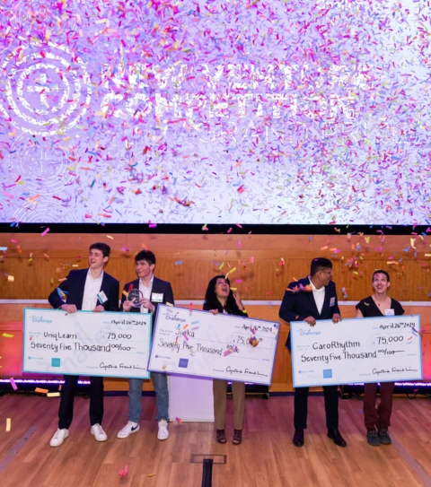 winners of the entrepreneurs challenge holding prize checks with confetti falling down