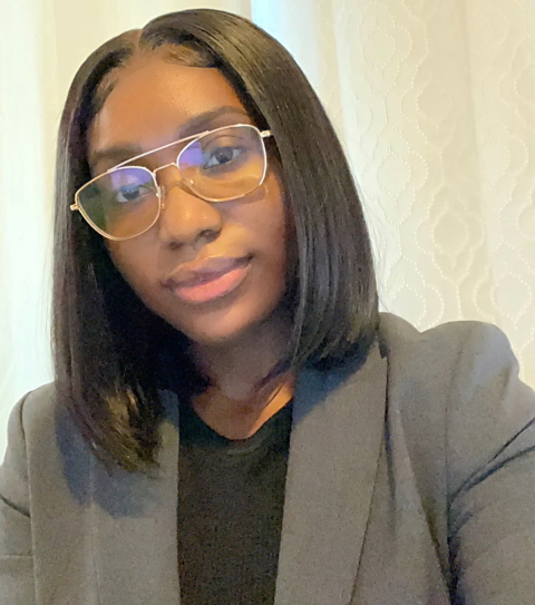 Nedjee Corriolan is a woman wearing a gray blazer