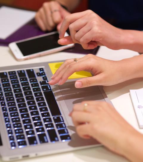 Hands type on a laptop keyboard