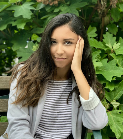 Rebeca sits on a bench outside