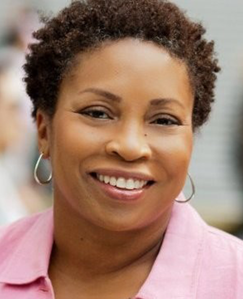 Kim Lewis-Collins A portrait of Kim Lewis-Collins - A Black woman in a pink shirt smiling at the camera